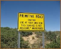 Yellow Primitive Road warning sign — caution, use at your own risk, this surface is not regularly maintained